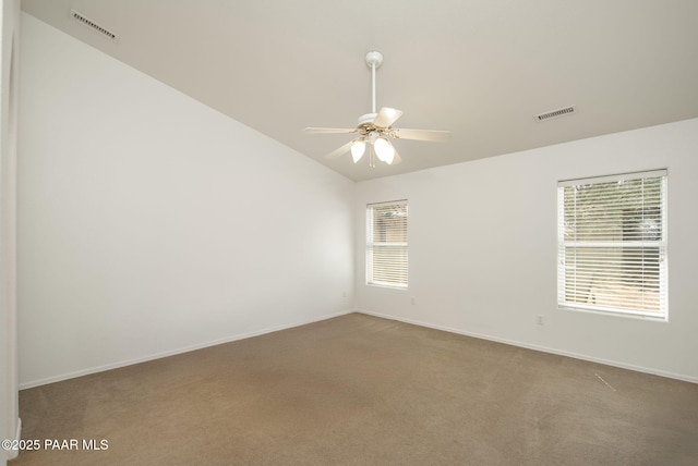 carpeted empty room featuring visible vents, baseboards, ceiling fan, and vaulted ceiling