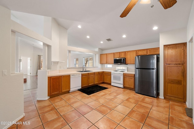 kitchen with sink, light tile patterned floors, appliances with stainless steel finishes, vaulted ceiling, and kitchen peninsula