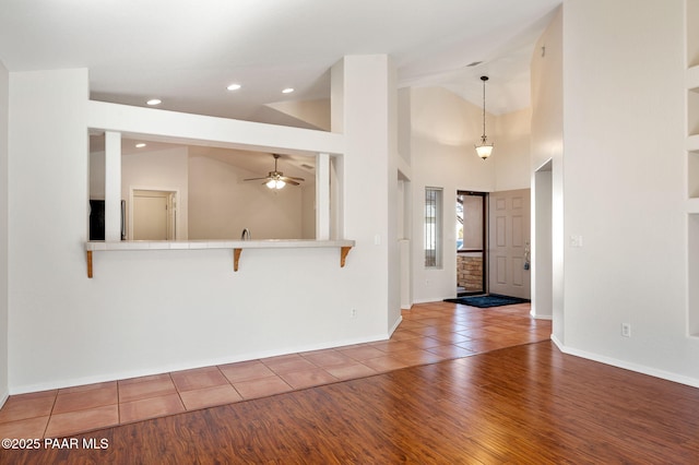 unfurnished living room featuring ceiling fan, tile patterned floors, and high vaulted ceiling