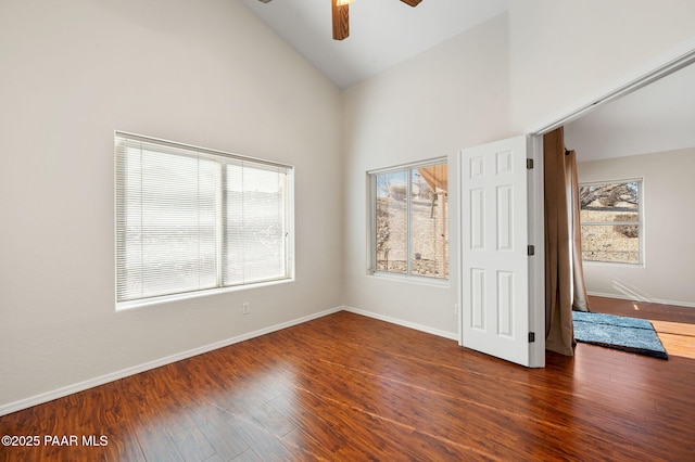 empty room featuring dark hardwood / wood-style flooring, high vaulted ceiling, and a healthy amount of sunlight