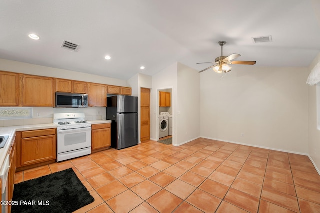 kitchen with vaulted ceiling, black refrigerator, white range with gas stovetop, ceiling fan, and washer and clothes dryer