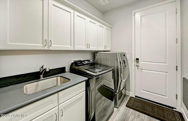 laundry room with a sink, cabinet space, washing machine and dryer, and wood finished floors