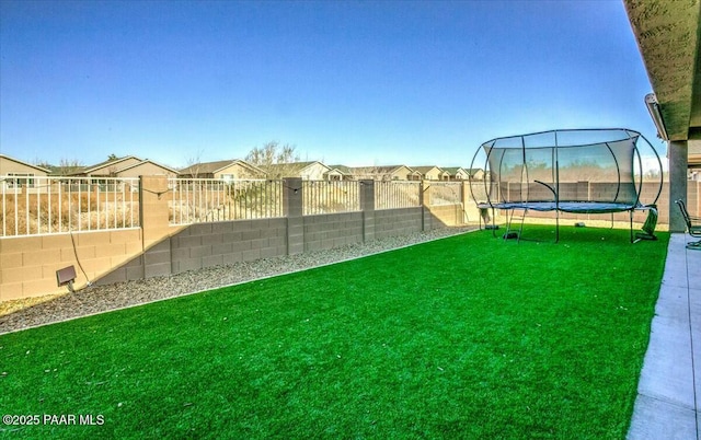 view of yard featuring a residential view, a trampoline, and a fenced backyard