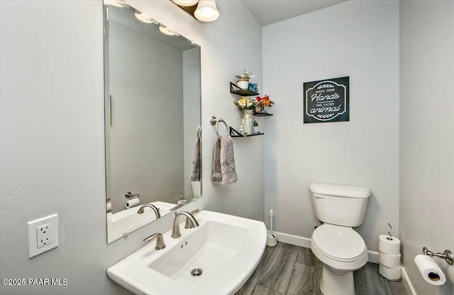 bathroom featuring a bidet, wood finished floors, baseboards, a sink, and toilet