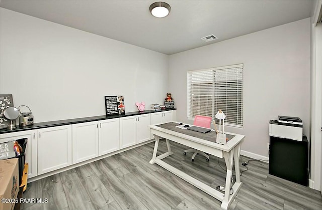 office with light wood-style floors and visible vents