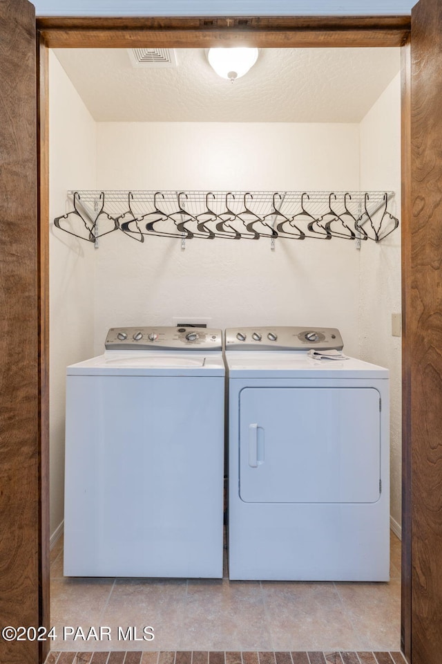 clothes washing area featuring washing machine and dryer and light tile patterned floors