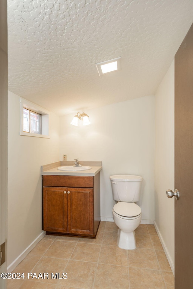 bathroom with vanity, a textured ceiling, toilet, and tile patterned flooring