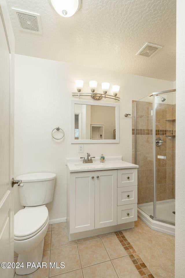 bathroom with vanity, a shower with door, tile patterned flooring, toilet, and a textured ceiling