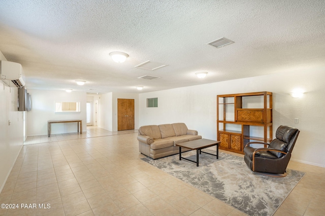 living room featuring an AC wall unit, light tile patterned floors, and a textured ceiling