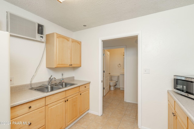 kitchen featuring sink, white refrigerator, a textured ceiling, light brown cabinetry, and light tile patterned flooring