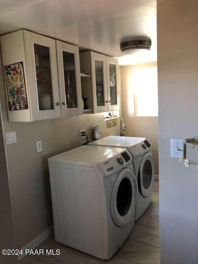 laundry area with washing machine and dryer, cabinets, and light hardwood / wood-style floors