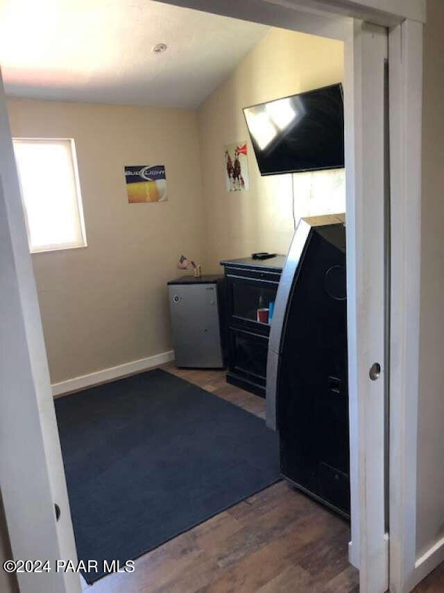 unfurnished bedroom featuring stainless steel refrigerator, dark wood-type flooring, and lofted ceiling