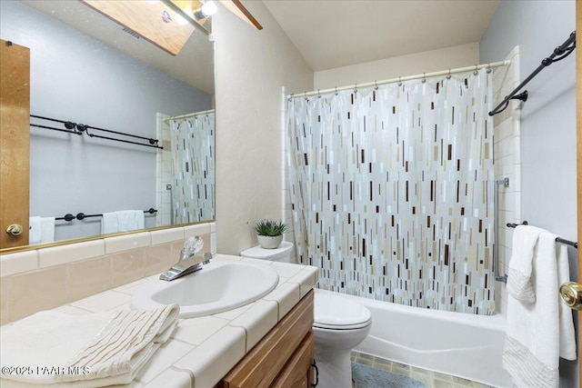 full bathroom featuring shower / bathtub combination with curtain, vanity, toilet, and a skylight