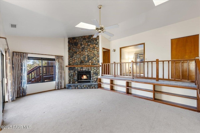 unfurnished living room with a skylight, high vaulted ceiling, ceiling fan, a fireplace, and carpet