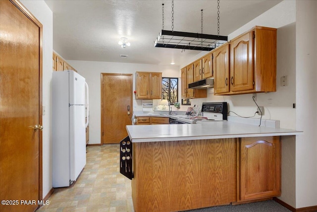 kitchen with range, sink, kitchen peninsula, and white fridge