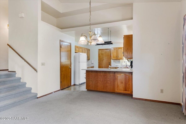 kitchen with sink, hanging light fixtures, white fridge, kitchen peninsula, and an inviting chandelier