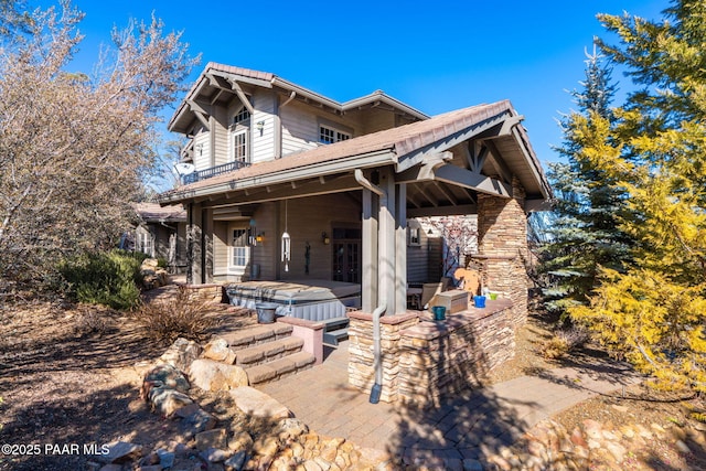 rear view of property with a hot tub and a patio