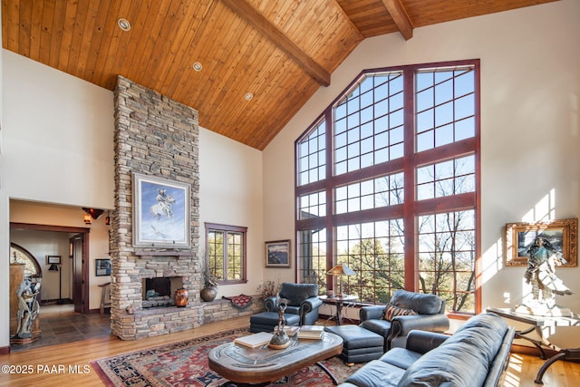 living room featuring beamed ceiling, wood ceiling, a fireplace, and high vaulted ceiling