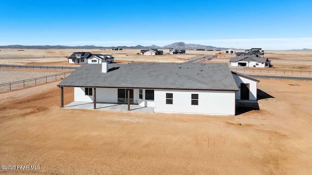 rear view of property featuring a patio area, a rural view, a mountain view, and fence