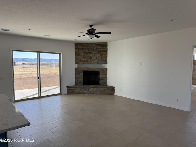 unfurnished living room with ceiling fan, a mountain view, a textured ceiling, and a fireplace