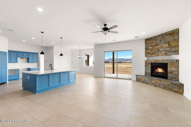 kitchen with a center island with sink, blue cabinetry, open floor plan, light countertops, and ceiling fan