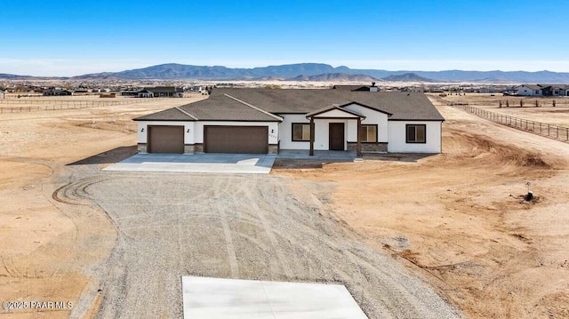 view of front of property with a mountain view, an attached garage, driveway, and stucco siding