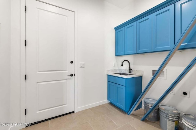 clothes washing area featuring electric dryer hookup, a sink, cabinet space, light tile patterned floors, and baseboards