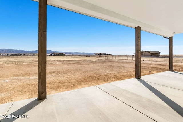 view of yard featuring a patio area, a rural view, a mountain view, and fence