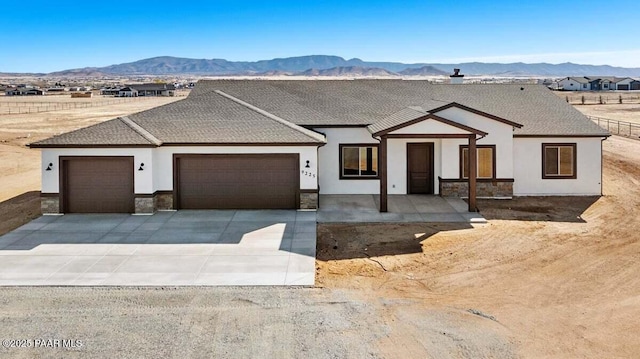 modern farmhouse style home featuring an attached garage, a mountain view, driveway, and stucco siding