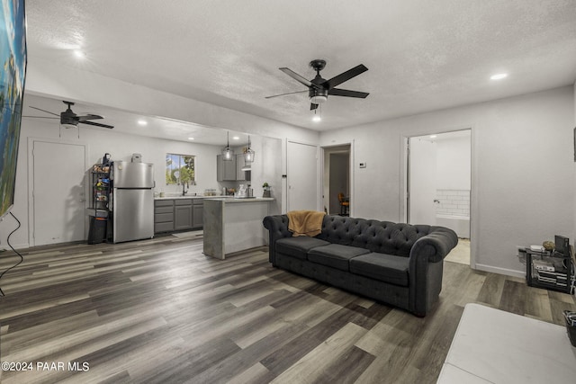 living room featuring a textured ceiling, ceiling fan, sink, and dark wood-type flooring