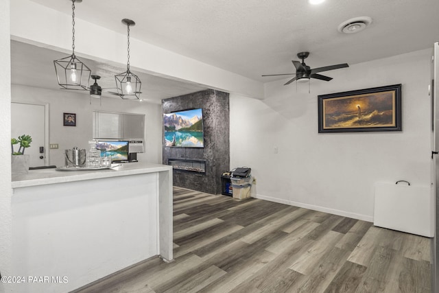 kitchen with ceiling fan, a large fireplace, hardwood / wood-style floors, a textured ceiling, and decorative light fixtures