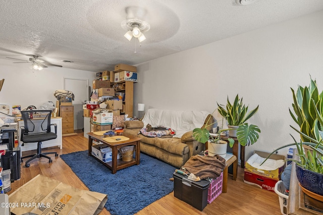 living room with a textured ceiling, light hardwood / wood-style floors, and ceiling fan