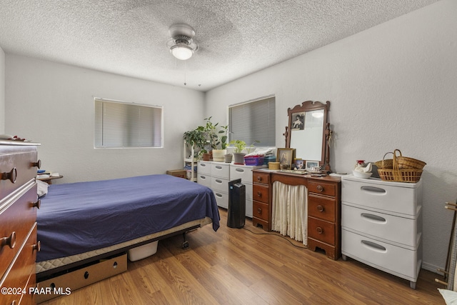 bedroom with ceiling fan, light wood-type flooring, and a textured ceiling