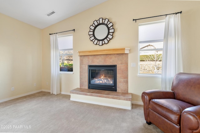 living room featuring visible vents, a tiled fireplace, vaulted ceiling, baseboards, and carpet flooring