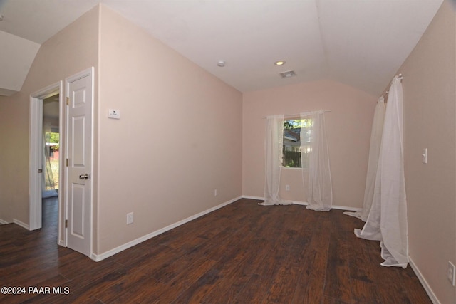 spare room with dark hardwood / wood-style floors and vaulted ceiling