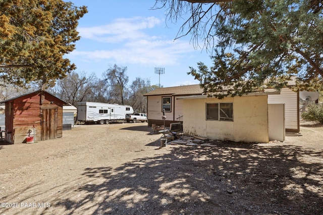 back of house with driveway and an outbuilding