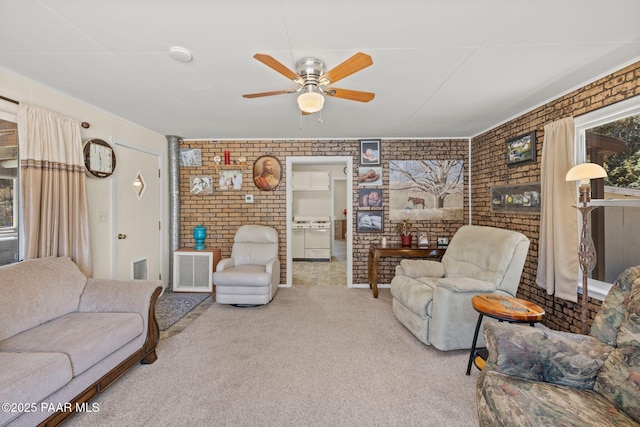 carpeted living room with a ceiling fan, brick wall, and visible vents