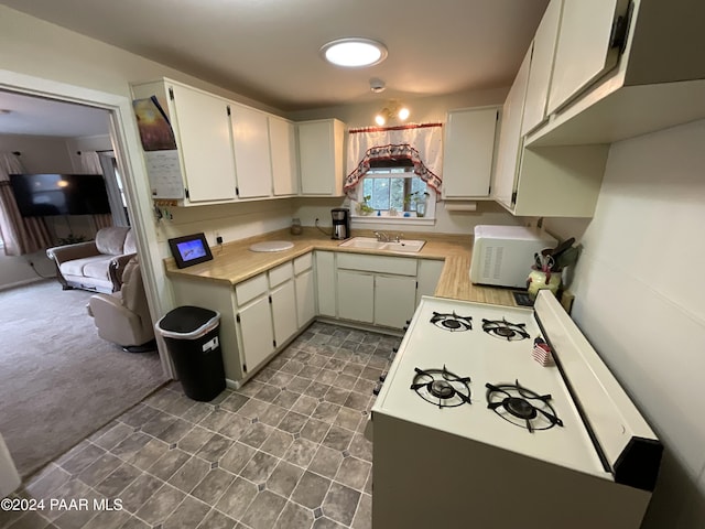 kitchen with sink, white cabinets, dark carpet, and white stove