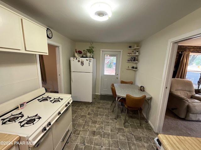 kitchen with white appliances, white cabinetry, and a wealth of natural light