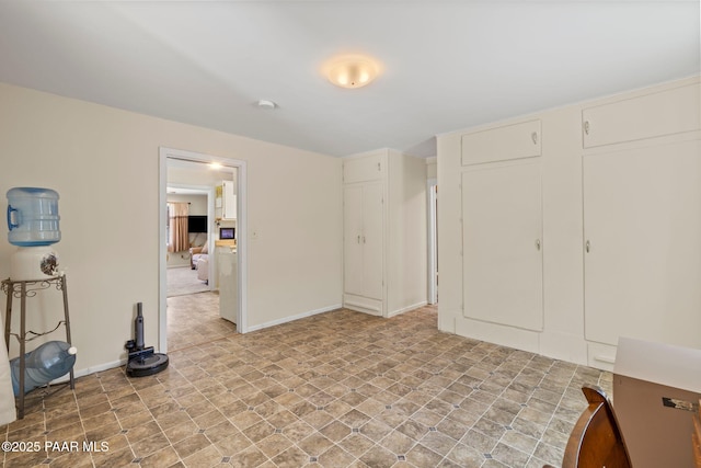 unfurnished bedroom featuring connected bathroom and baseboards
