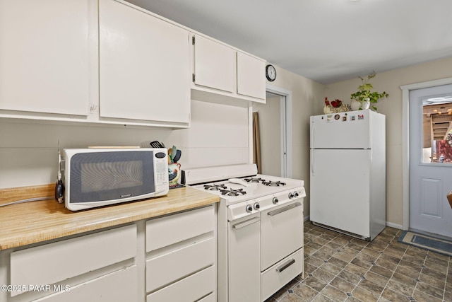 kitchen featuring stone finish floor, white appliances, white cabinetry, and light countertops