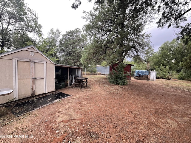 view of yard featuring an outdoor structure, a storage unit, and fence