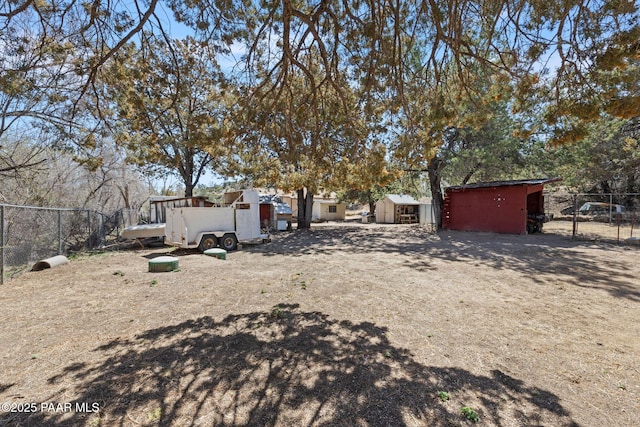 view of yard featuring an outdoor structure, fence, and a storage shed