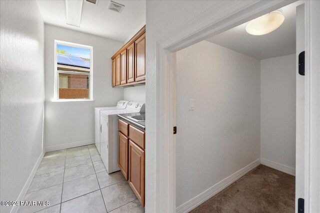 washroom with light tile patterned floors, cabinets, and independent washer and dryer