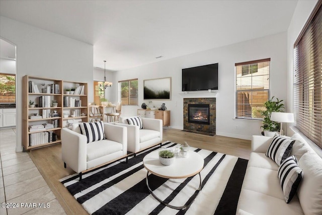 living room featuring light hardwood / wood-style floors, a healthy amount of sunlight, a fireplace, and a chandelier