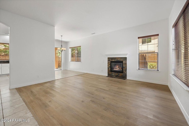 unfurnished living room featuring an inviting chandelier, light hardwood / wood-style flooring, and a healthy amount of sunlight