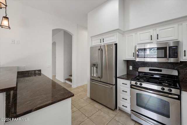 kitchen featuring tasteful backsplash, stainless steel appliances, pendant lighting, white cabinetry, and light tile patterned flooring