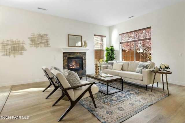 living room with a tiled fireplace and light hardwood / wood-style flooring