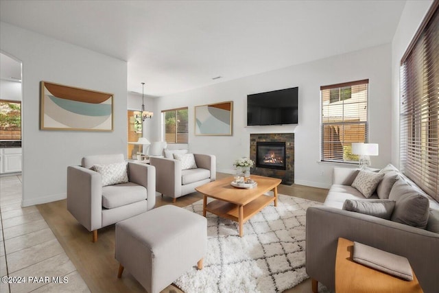 living room featuring a stone fireplace, light wood-type flooring, and a wealth of natural light