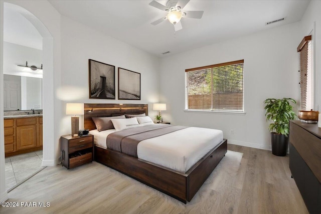 bedroom with connected bathroom, ceiling fan, light hardwood / wood-style flooring, and sink